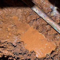 Exposed pipe leak in crawlspace with water pooling